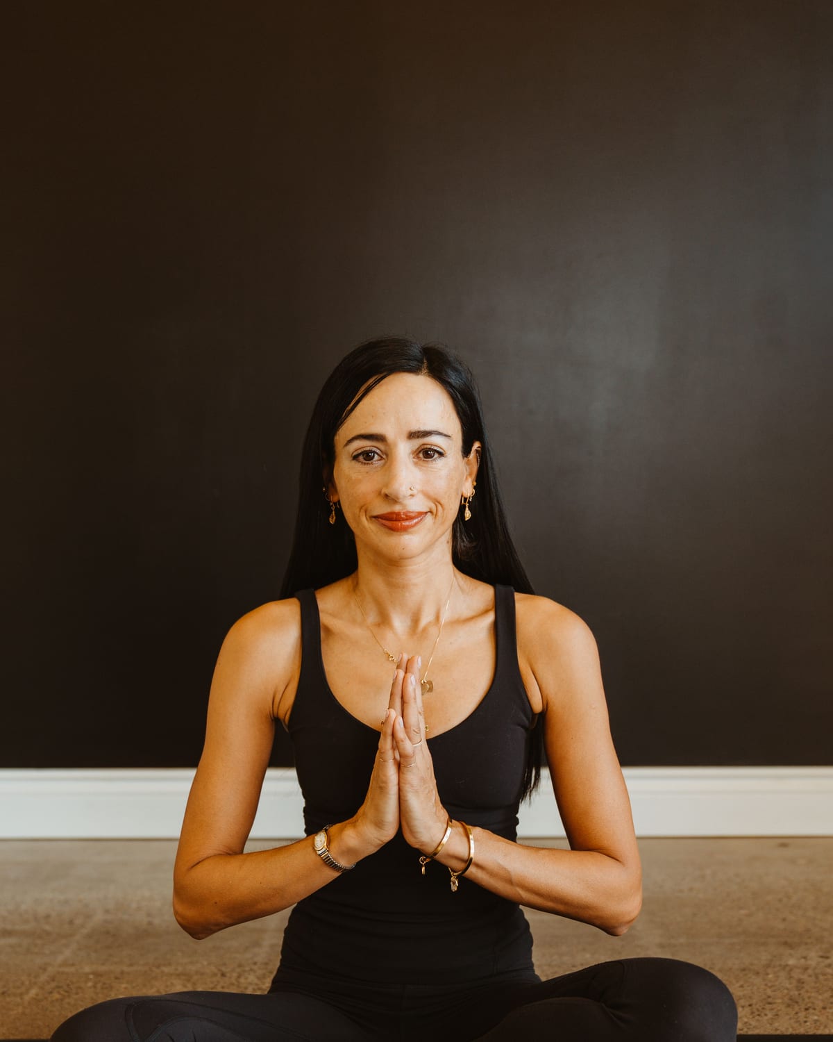 A teacher seated in meditation with prayer hands