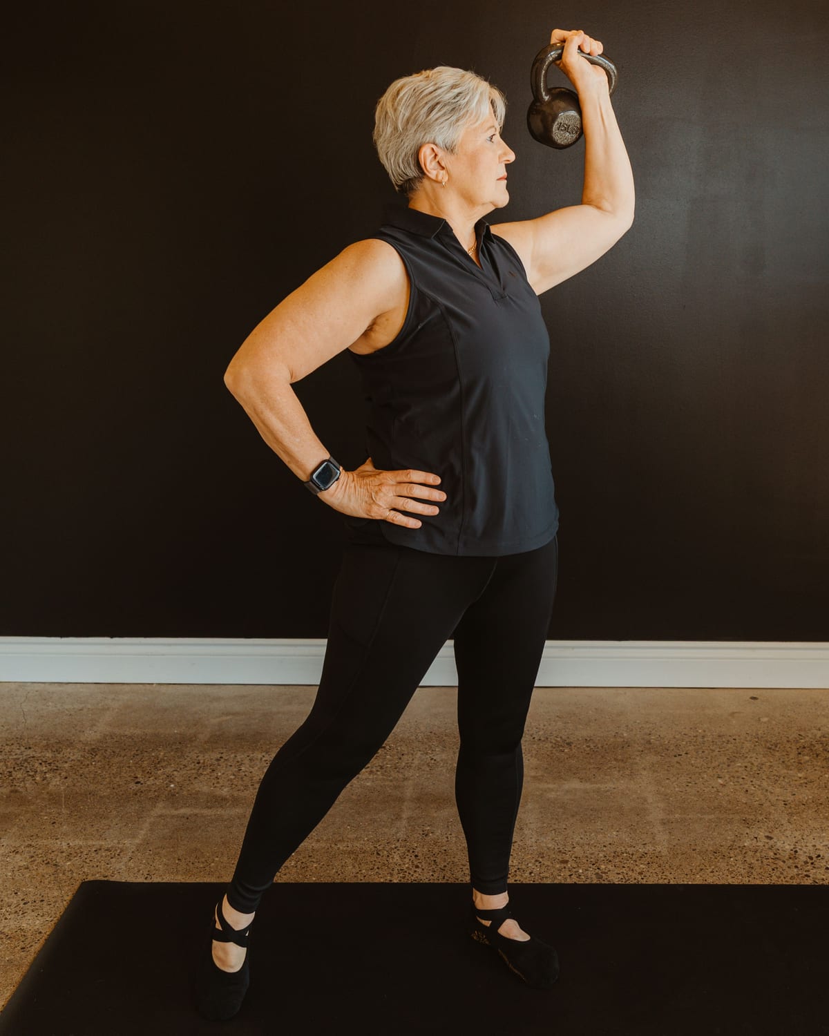 A teacher pressing a kettlebell overhead