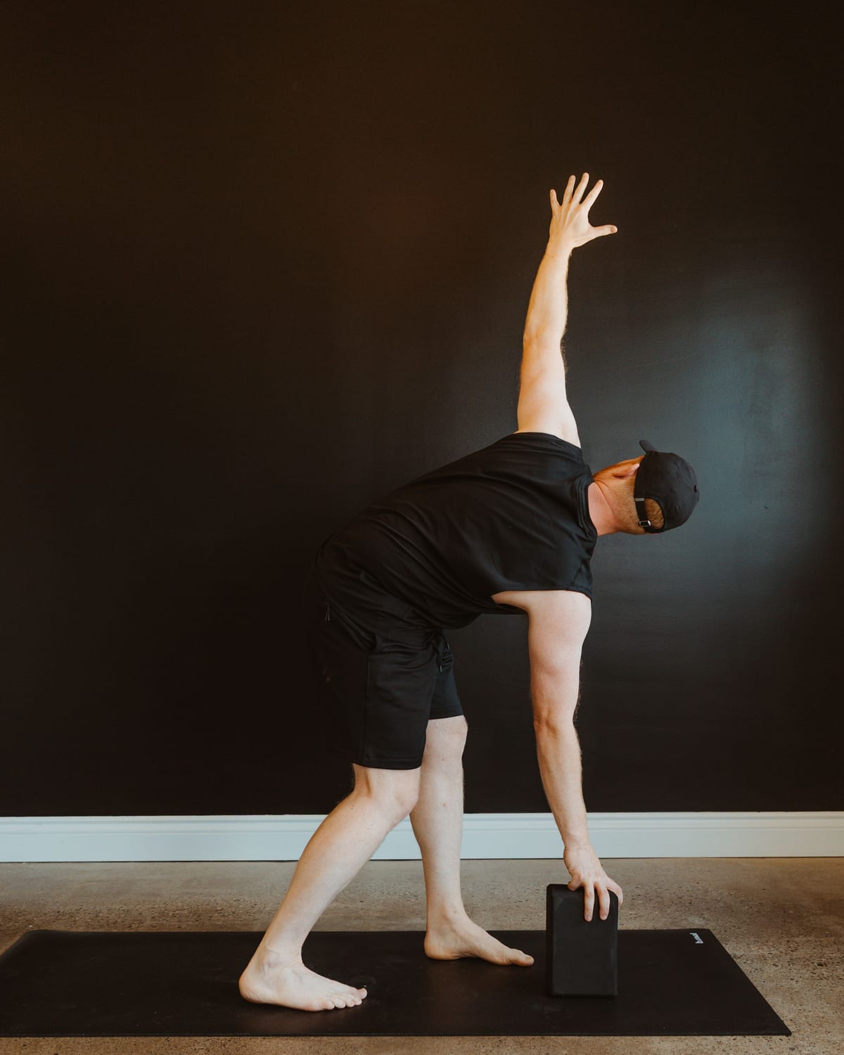 A teacher in a standing side-bend with a block