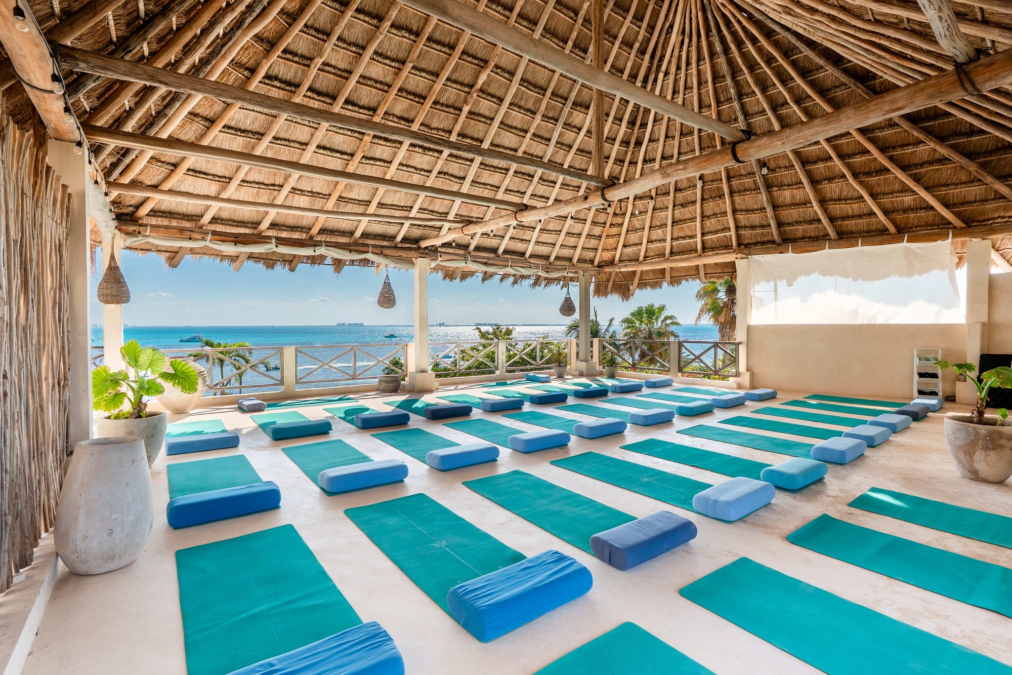 Open-air rooftop yoga shala at Casa Coco, rows of mats facing the Caribbean