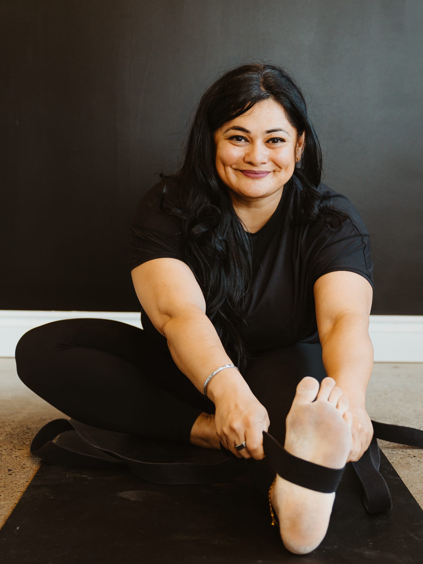 A smiling member seated on her mat at The Lineage